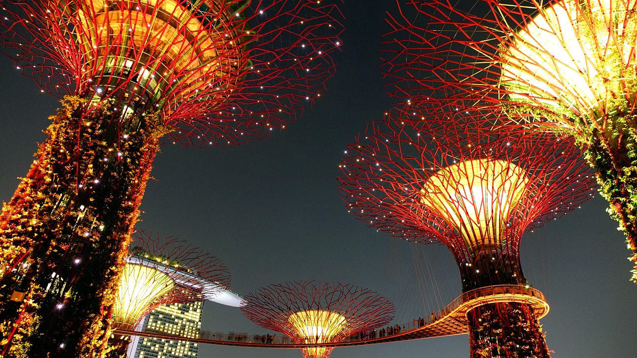 Futuristic glowing Supertrees at Gardens by the Bay in Singapore surrounded by lush tropical gardens.